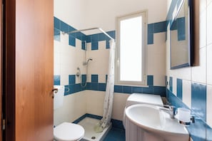 Ein Badezimmer mit Dusche, Toilette, Waschbecken und einem Fenster.