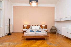 Ein Schlafzimmer mit einem hölzernen Bett, zwei Nachttischen mit Lampen, einem Sessel und einer Heizung.