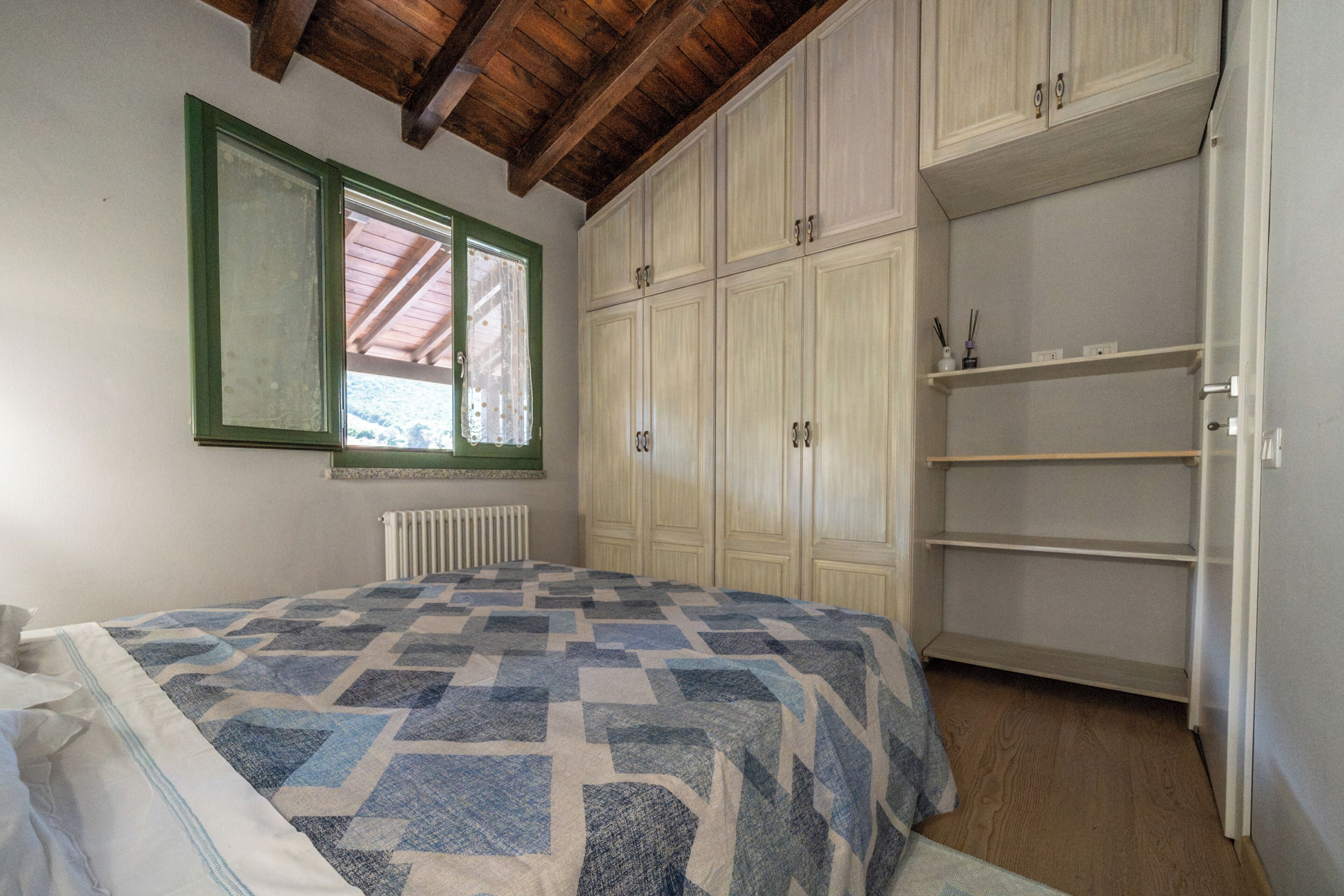 Une chambre à coucher avec un lit, une fenêtre, un radiateur et une armoire.