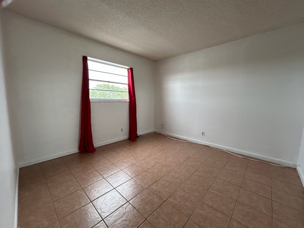 A room with a window, red curtains, and a tiled floor.
