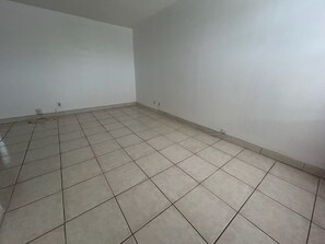 Una habitación con suelo de baldosas, paredes blancas y enchufes.