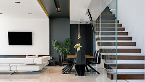 Una sala moderna con sofá, mesa de comedor, sillas y una escalera.