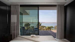 Un dormitorio con un amplio ventanal corredera que da a un balcón con vistas al mar.