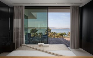 Ein Schlafzimmer mit einer großen Schiebeglasdoor zum Balkon mit Blick aufs Meer.