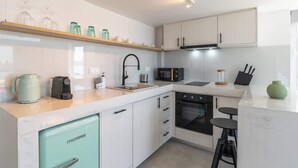 A modern kitchen with a refrigerator, microwave, oven, and a coffee maker. - Akti Waterfront Modern Lofts: Pelagos (Adamantas Milos)