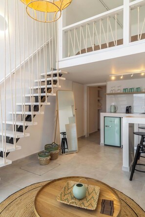 Un interior modern amb una escala, una cuina compacta i una zona de menjador.