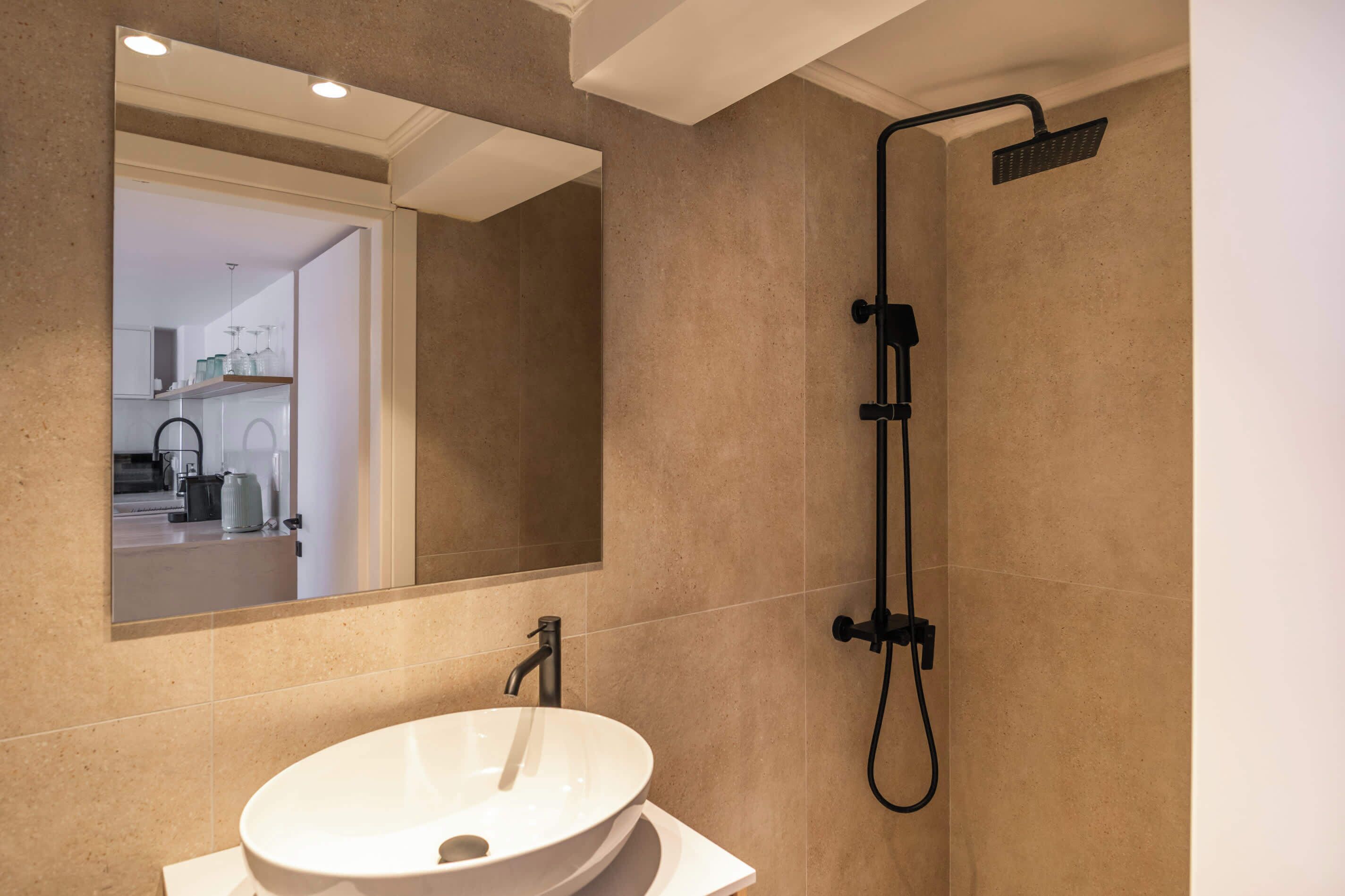 A bathroom with a white sink, a mirror, and a shower.