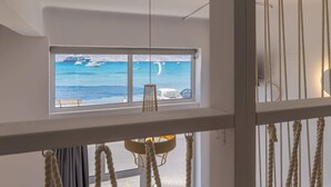 Ein Zimmer mit einem großen Fenster und Blick auf das Meer und Boote.