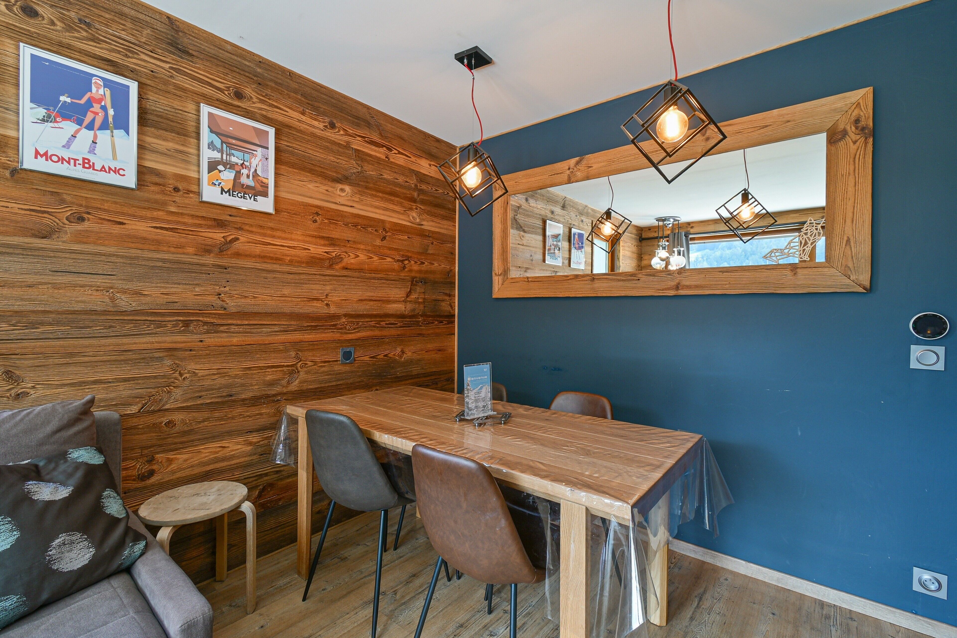 Una habitación con paneles de madera, una mesa de comedor de madera, sillas y un espejo grande.