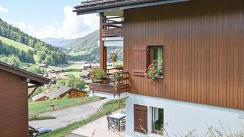 Een houten gebouw met een balkon, een tafel en stoelen.