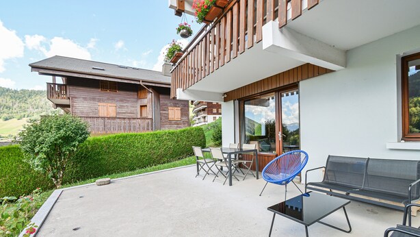 En moderne udendørs terrasse med spisebord, stole og en sofa.