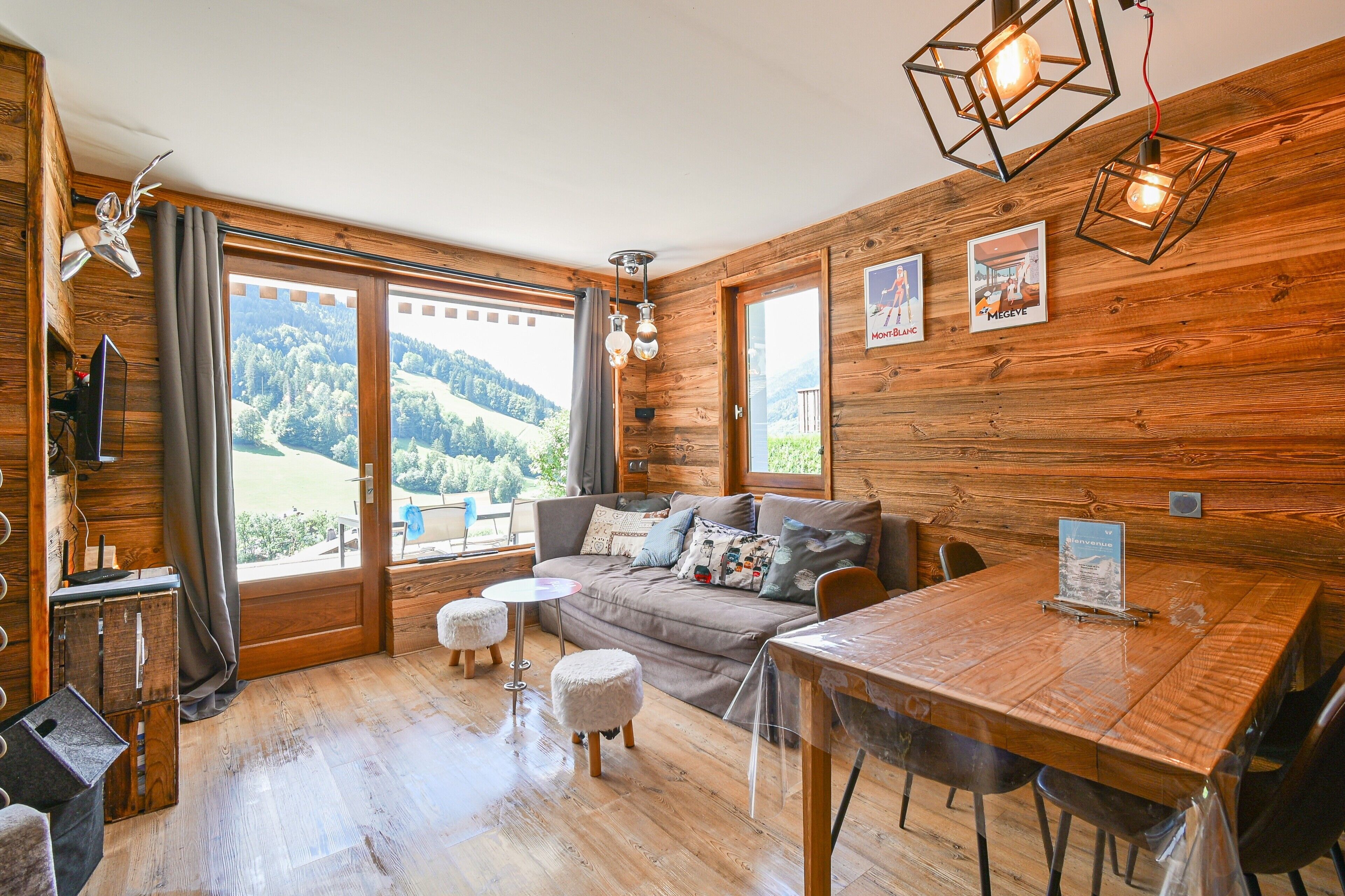 Une pièce chaleureuse avec des murs en bois, un canapé, une table à manger et une vue sur l’extérieur.