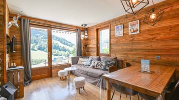 Une pièce chaleureuse avec des murs en bois, un canapé, une table à manger et une vue sur l’extérieur.