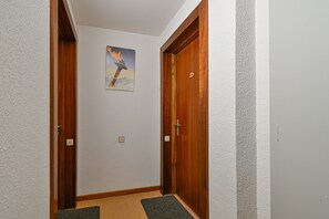 Ein Korridor mit Holztüren, einem Lichtschalter und einem gerahmten Bild an der Wand.