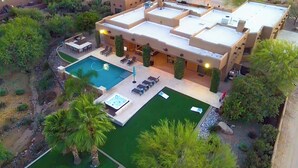 Une maison moderne dotée d’une piscine sur le toit, d’un espace salon extérieur et d’un jardin bien entretenu.