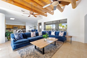 A modern living room with a sectional sofa, a wooden coffee table, and a large window with a view. - Desert Villa Pool, Hot Tub & Putting Green (Scottsdale)