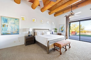 A bedroom with a large bed, a wooden ceiling, a ceiling fan, and a view through a large window. - Desert Villa Pool, Hot Tub & Putting Green (Scottsdale)