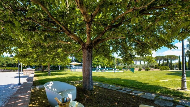 A tree-lined outdoor seating area with a stone pathway and a view of a park. - GuestHost - Il Casale dei Gelsi - Ciclamino (San Martino In Campo)