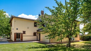 A two-story building with a flat roof, a small porch, and a tree in the foreground. - GuestHost - Il Casale dei Gelsi - Ciclamino (San Martino In Campo)