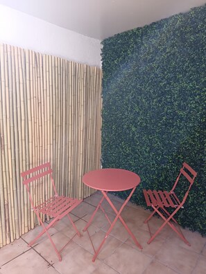 Een klein terras met een bamboe wand en een wand vol groene beplanting.
