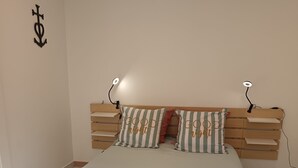 Et soveværelse med en seng, sengetæppe med striber, et træhovedgærde, sengeborde med lamper og en vægdekoration.