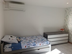 Ein Schlafzimmer mit einem Bett, einem Schminktisch, einer Klimaanlage und einer Wand mit Muster.