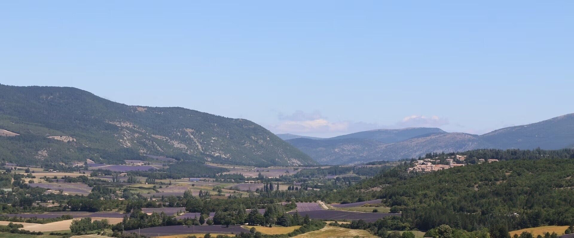 A mountainous landscape with fields and scattered buildings.