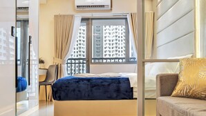 Et moderne hotelværelse med seng, sofa, vindue med byudsigt, skrivebord og stol.