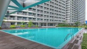 Et moderne hotel med en stor udendørs swimmingpool, flere balkoner og et tidssvarende arkitektonisk design.