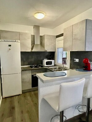 Eine moderne Küche mit Kühlschrank, Mikrowelle, Herd und Kaffeemaschine.