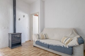 Een kamer met een bank, een open haard en een deur.