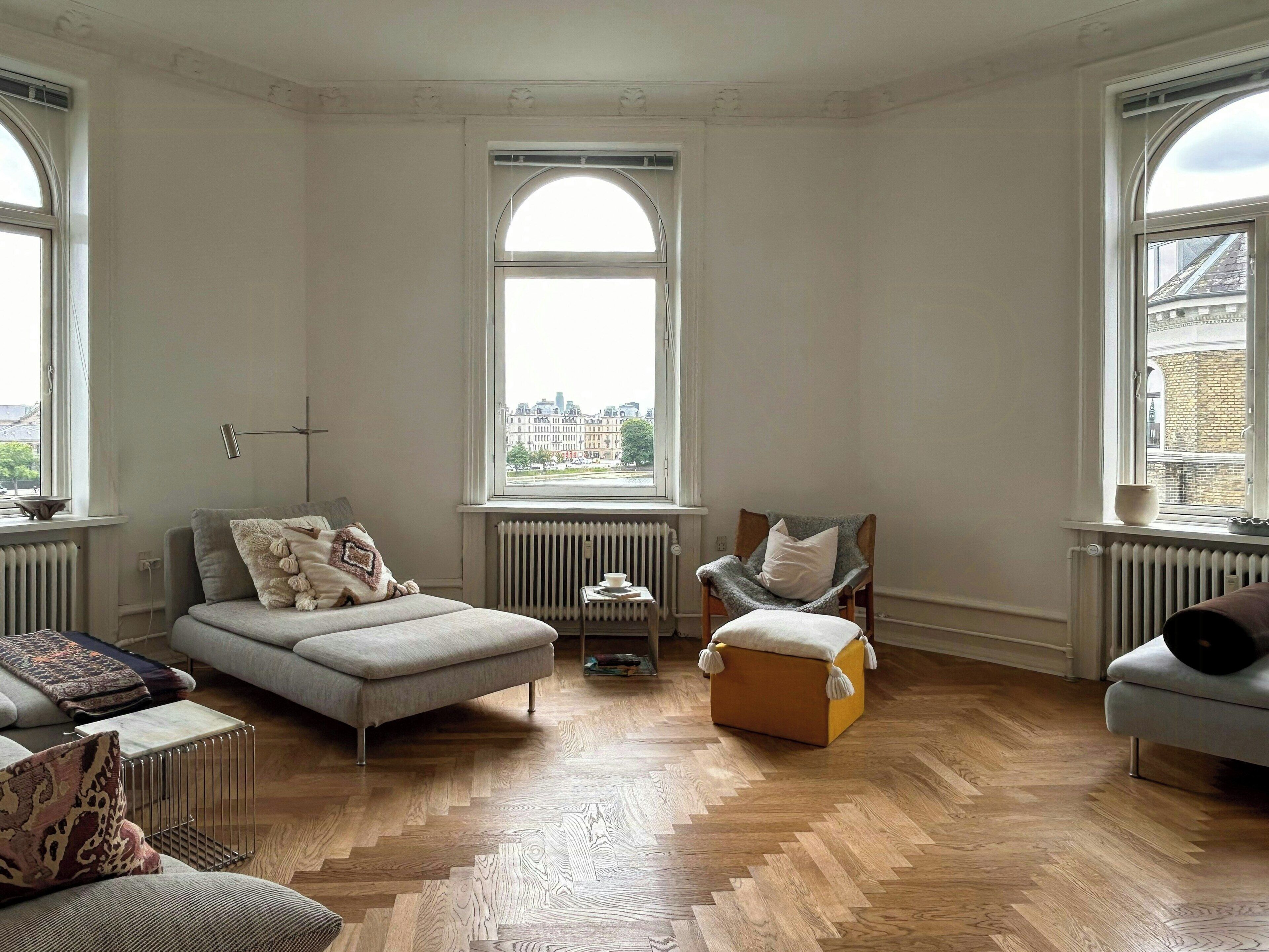 Una habitación con una cama, dos sillones, una mesita y un radiador.