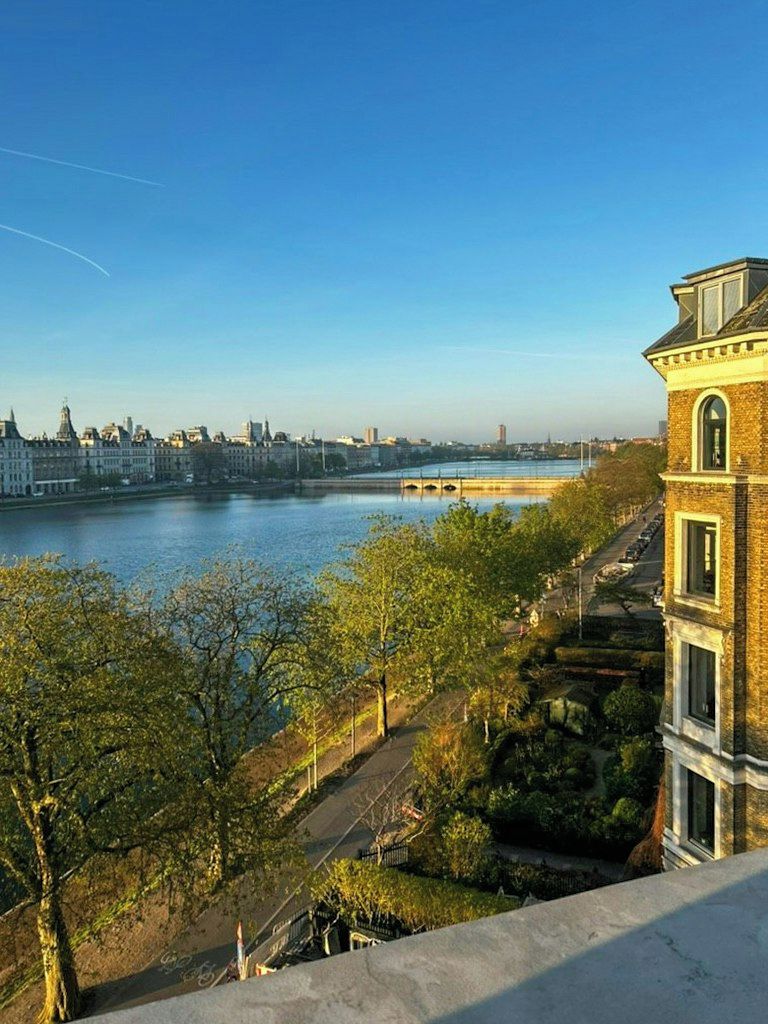 A riverside view with a building featuring a prominent corner and a staircase leading down to a pathway.