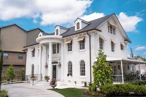 A large, white, two-story house with a wrap-around porch and a covered outdoor seating area.