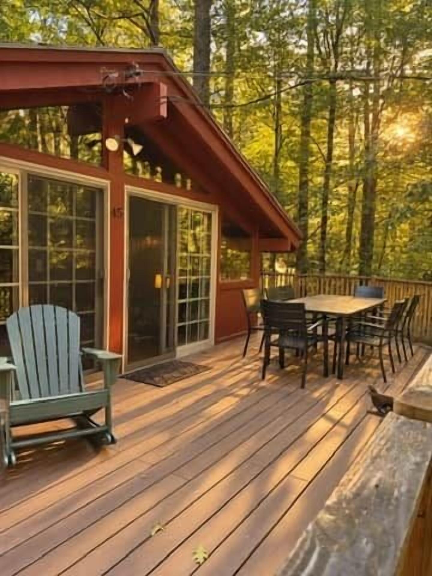 A wooden deck with a table and chairs, a covered seating area, and a building with large glass doors.