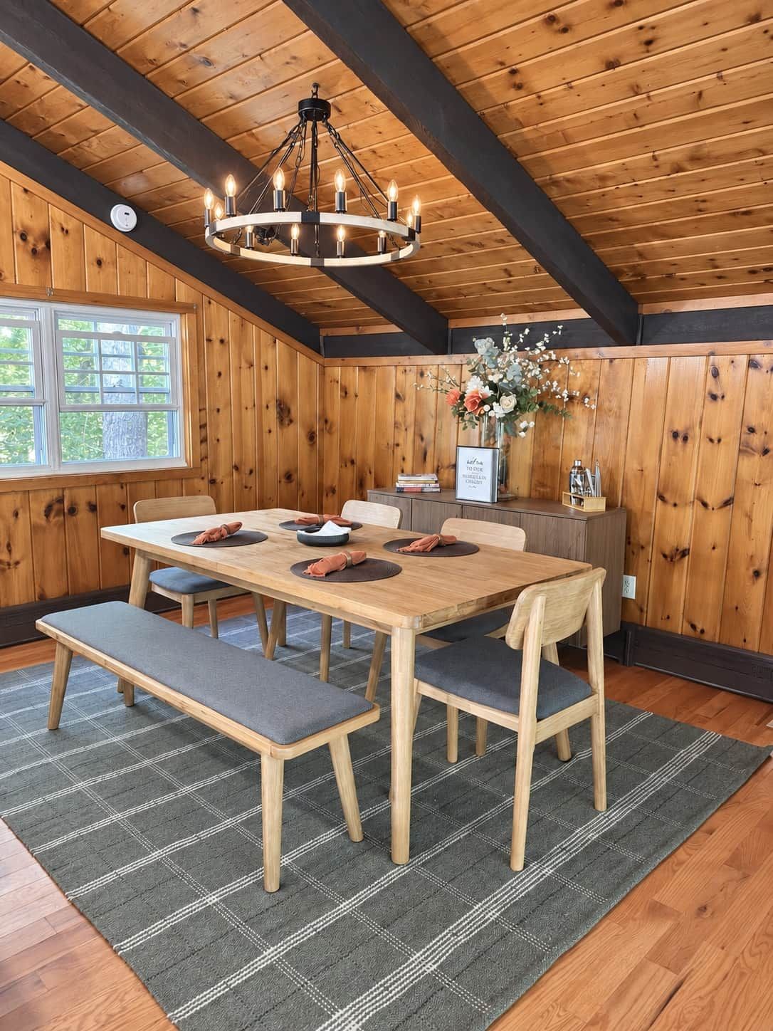 A dining area with a wooden table, benches, and a chandelier.