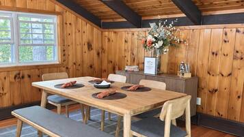 A dining area with a wooden table, benches, and a chandelier.