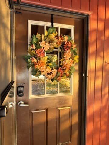 A wooden door with a window and a doorbell.
