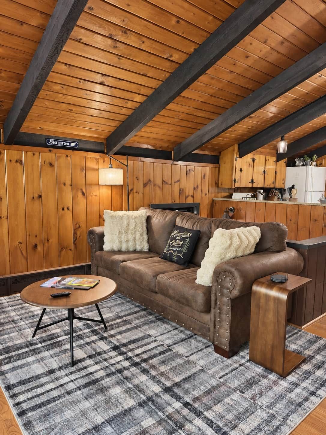 A cozy room with a leather sofa, a small round coffee table, and a checkered rug.