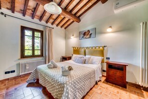 Ein Schlafzimmer mit einem Bett, einem Nachttisch, einem hölzernen Kopfteil, einem Fenster und einer Heizung.