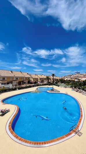 A swimming pool with a dolphin design, surrounded by a tiled deck and a clear blue sky. - Las Americas Pool & Private Patio Apartment 7 (Playa de las Américas)