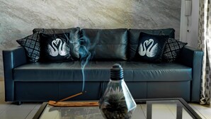 Ein Wohnzimmer mit einer Couch, Zierkissen, einem Glastisch und einem Räucherdiffusor.