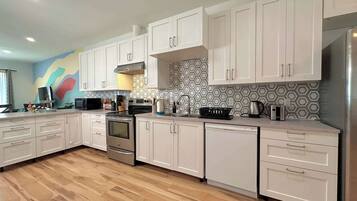 A modern kitchen with white cabinets, stainless steel appliances, and a colorful backsplash.