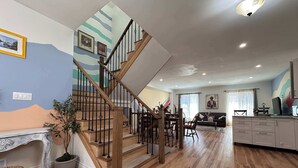 Un vaste espace de vie comprenant un escalier en bois, une table à manger et un coin cuisine.