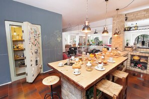 A kitchen with a central island, bar stools, a refrigerator with magnets, and a brick wall. - Villa Elena - Luxury Mansion in Rome (Rome)