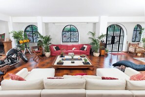 A spacious living area with a red sofa, white couches, a coffee table, and potted plants. - Villa Elena - Luxury Mansion in Rome (Rome)
