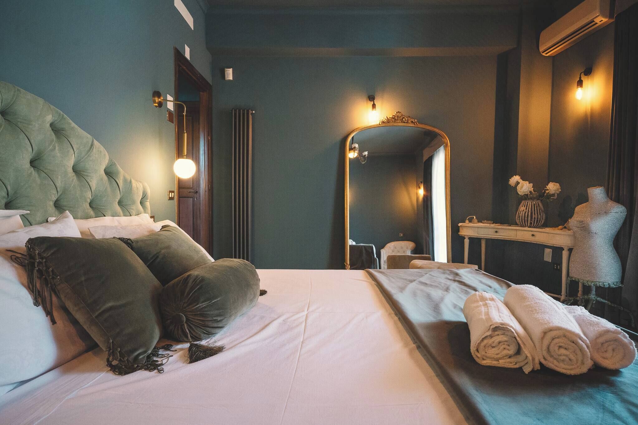 A hotel room with a bed, a vanity with a mirror, and a mannequin.