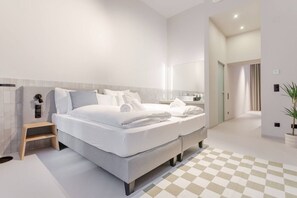 Ein modernes Hotelzimmer mit einem großen Bett, Nachttischen, einem Spiegel und einer Zimmerpflanze.