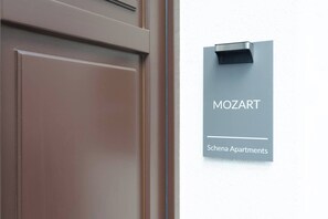 Eine Tür mit einem Schild darüber, auf dem 'MOZART Schena Apartments' steht.
