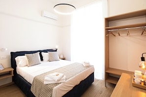 Quarto de hotel com cama, mesas de cabeceira, guarda-roupa e abajur.